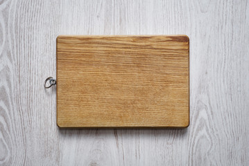 Wooden chopping board on brushed white table top view