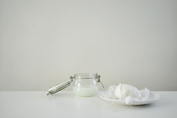 Fresh mozarella on white souser and jar with brine