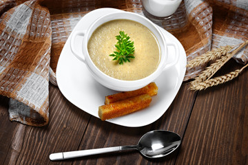 Vegetable soup with parsley and fried bread on a wooden table.