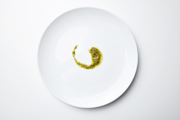 pesto sause spoiled on white blank plate isolated top view