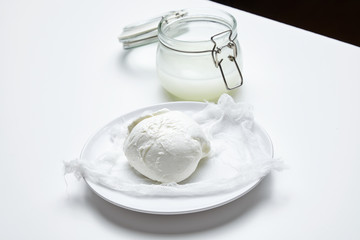 Fresh buffalo mozzarella in front of jar with brine isolated sid