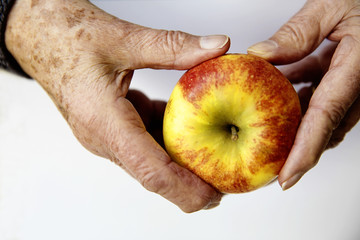 Hände einer Seniorin mit einem Apfel