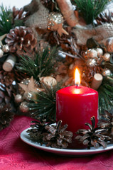 Red candle with fir cones and Christmas wreath