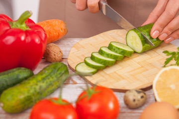 Pretty lady is cooking salad in kitchen