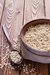 oatmeal in a cup and spoon closeup vertically on a wooden table