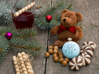three fir-tree branches, cup of tea, sweets and toy bear