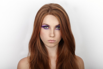 Naklejka premium Portrait of serious young beautiful redhead woman with gorgeous hair and violet eyes makeup against white studio background