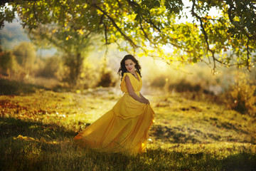 Young woman in the yellow dress with autumn leaves 