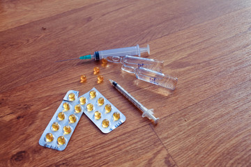Syringe with glass vials and medications pills drug on wood tabl
