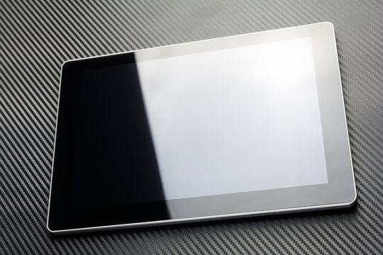 Blank Business Tablet With Reflection Lying On Carbon Background