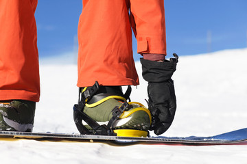 a snowboarder strapping his bindings on the mountain