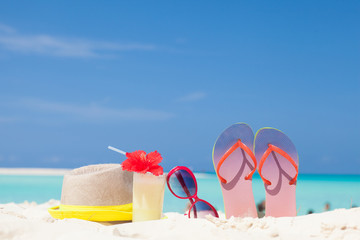 colourful picture of flip flops, sun hat, pina colada cocktail with hibiscus and pink sunglasses near the beach