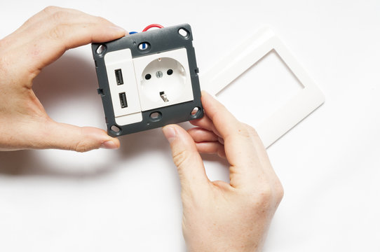 A man hold the socket with two usb charger ports, without decorating pane.