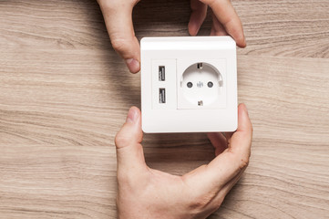 A man hold the electric socket with two usb-charger ports.