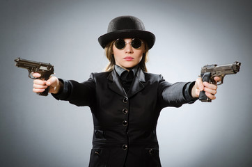 Female spy with weapon against gray