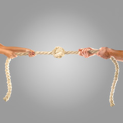 Hands of people pulling the rope on a gray background.  Competition concept