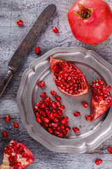 Juicy pomegranates,whole and broken vintageon a metal plate.selective focus.