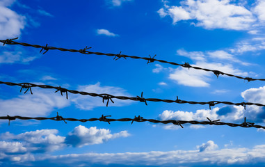 Barbed wire on blue sky background.
