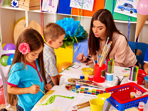 Children with teacher woman painting on paper in  kindergarten