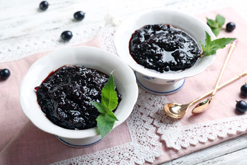 Tasty currant jam with berries on table close up