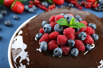 Delicious chocolate cake with summer berries on blue tablecloth, closeup
