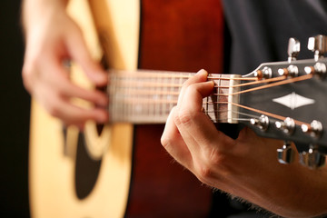 Young musician playing acoustic guitar close up