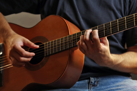 Young musician playing acoustic guitar close up