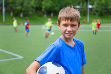 Boy footballer with a ball on soccer field