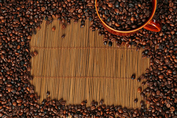 A frame of aromatic coffee beans and a cup on bamboo mat