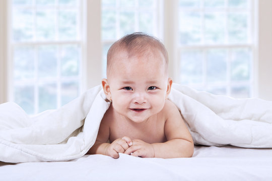 Sweet baby laughing under blanket