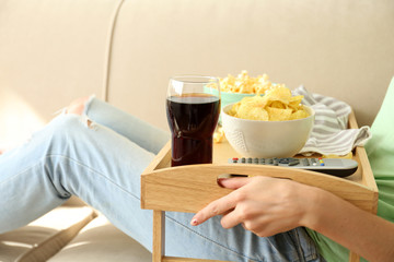 Obraz na płótnie Canvas A girl with a tray having lunch on a sofa, close-up