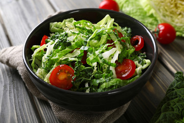 Savoy cabbage and tomato salad served in bowl on wooden table