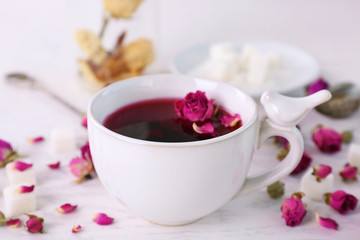 Tea and tea rose flowers on table closeup
