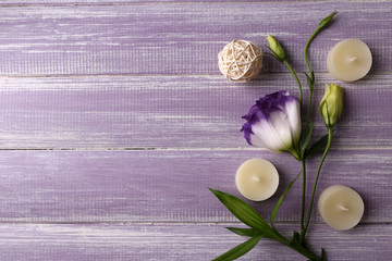 Spa composition of candles and flower on purple wooden background