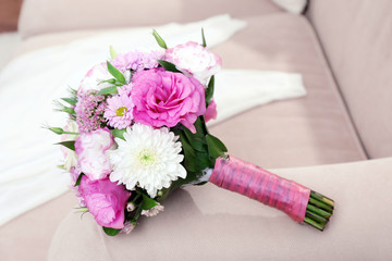 Wedding bouquet and bridesmaid dress on sofa in room