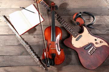 Electric guitar, violin, soprano saxophone, headphones and book on wooden background