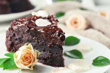 Piece of chocolate cake decorated with flowers on white wooden table