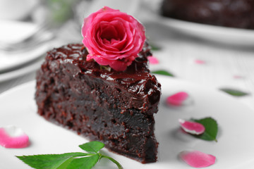 Piece of chocolate cake decorated with flowers on white wooden table