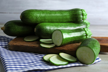 Fresh sliced zucchini on cutting board, on wooden background