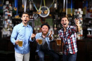 Young men with beer rejoice the victory of their favorite team in the pub