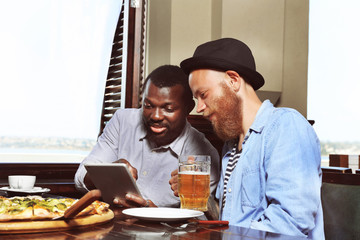 Young men drinking beer and talking in cafe