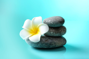 Obraz na płótnie Canvas Spa stones and flower on blue background