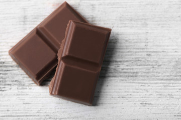 Black chocolate pieces on color wooden background