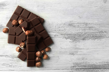 Chocolate pieces with nuts on color wooden background