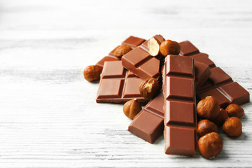 Chocolate pieces with nuts on color wooden background