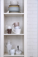 Different clean dishes on wooden shelves