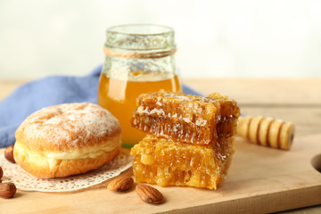 Glass jar with honey, honeycombs and nuts on wooden background
