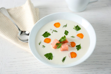 Delicious cream soup with salmon and carrot in white bowl