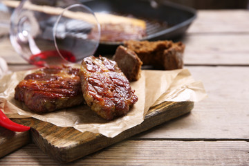 Roasted beef fillet and vegetables on cutting board, on wooden background