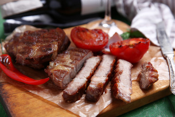 Roasted beef fillet and vegetables on cutting board, on wooden background